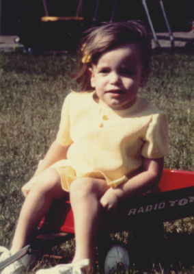 Lorrie in her little red wagon in her backyard.